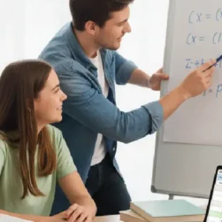 Jeune homme expliquant une formule mathématique à une adolescente souriante, ils sont assis à une table dans un cadre lumineux et moderne, avec des livres de maths et un ordinateur portable, symbolisant l'apprentissage et la tarification juste.